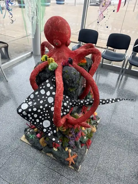 Fran Cooper's sculpture named "Octapus at The Deep", features a red octopus sitting on a coral seabed.