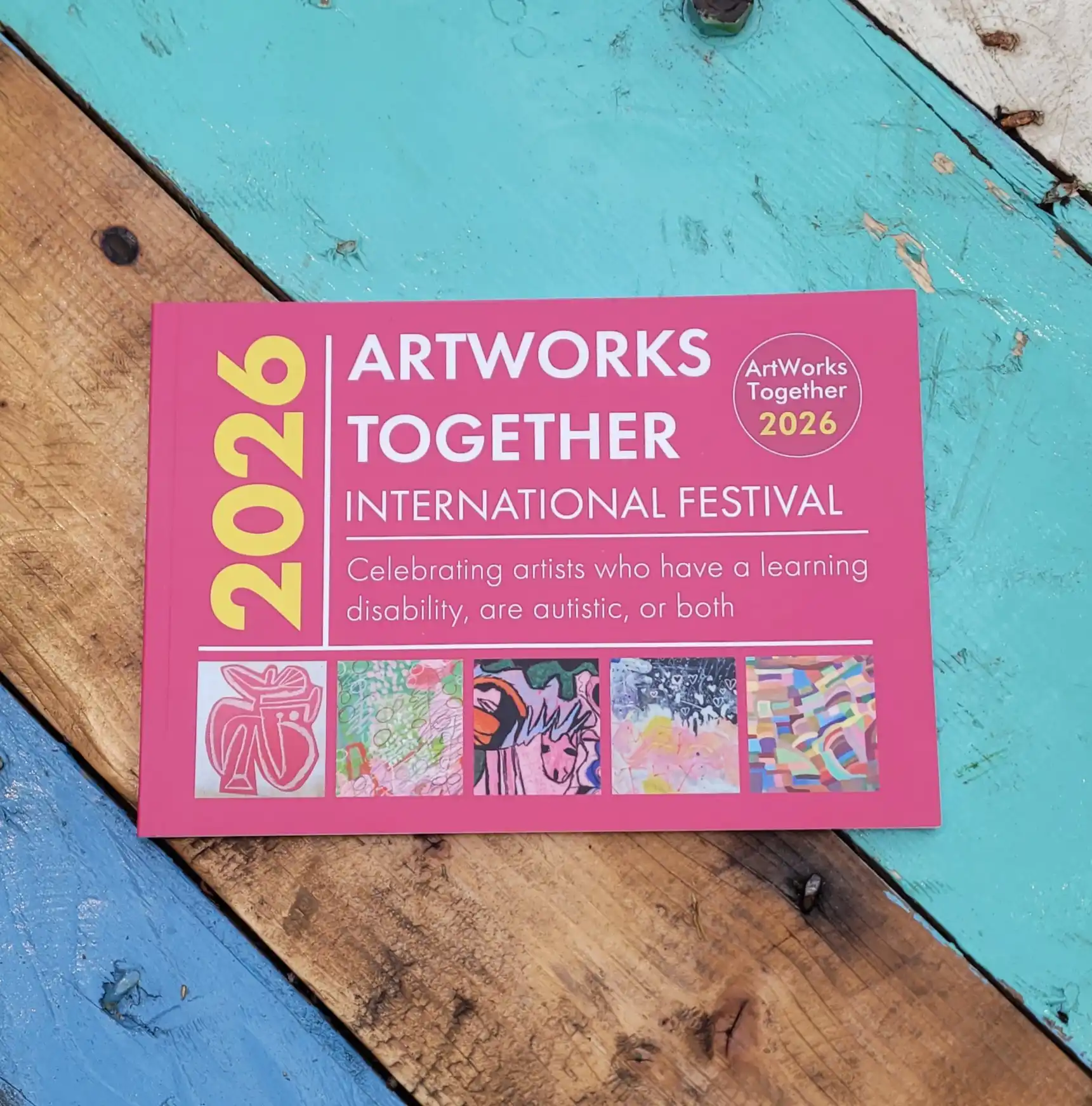 Front cover of the ArtWorks Together 2026 catalogue in pink with bold text and 5 artworks from the exhibition along the bottom.