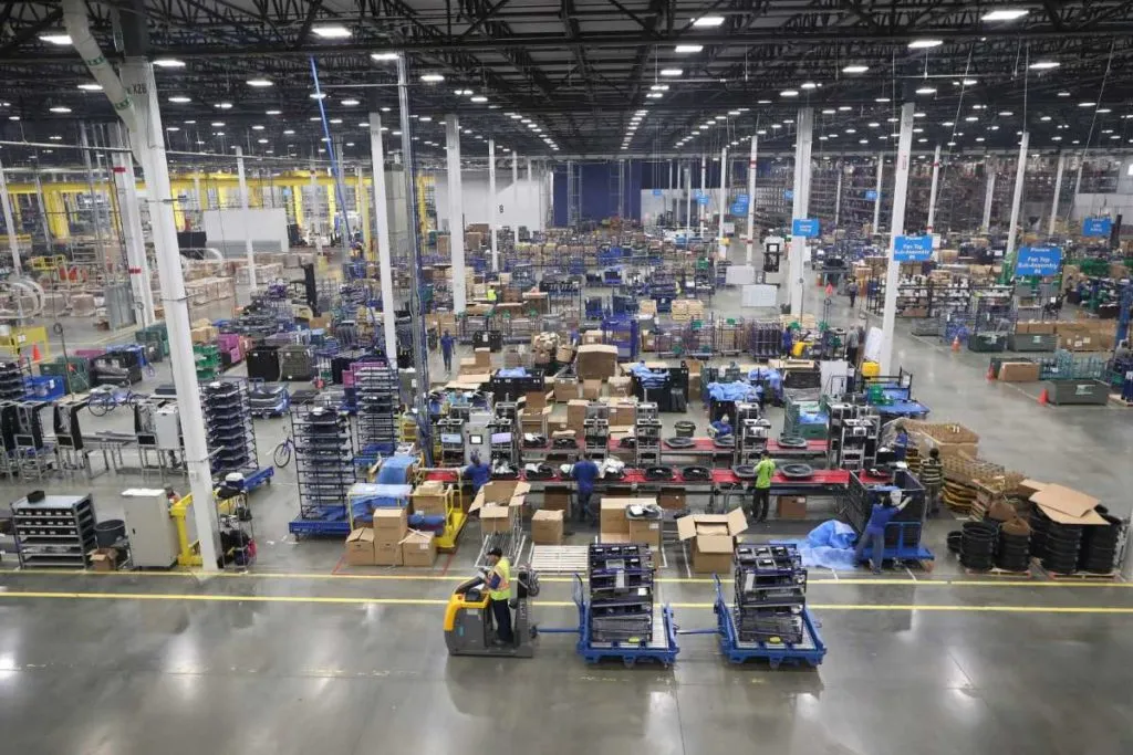 Large industrial warehouse with workers, machinery, and stacked boxes