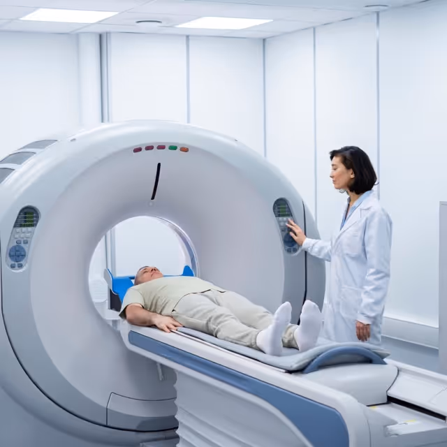 Ein Mann liegt für eine CT-Untersuchung auf einer Liege in einem medizinischen Gerät, eine Ärztin bedient die Maschine.