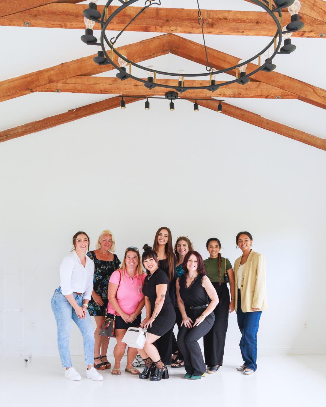 Group photo of diverse women smiling at the United Women’s Network of Florida (UWNF) inaugural women’s networking event. Attendees gather in a bright room with wooden ceiling beams, showcasing the community and connection of UWNF Florida.