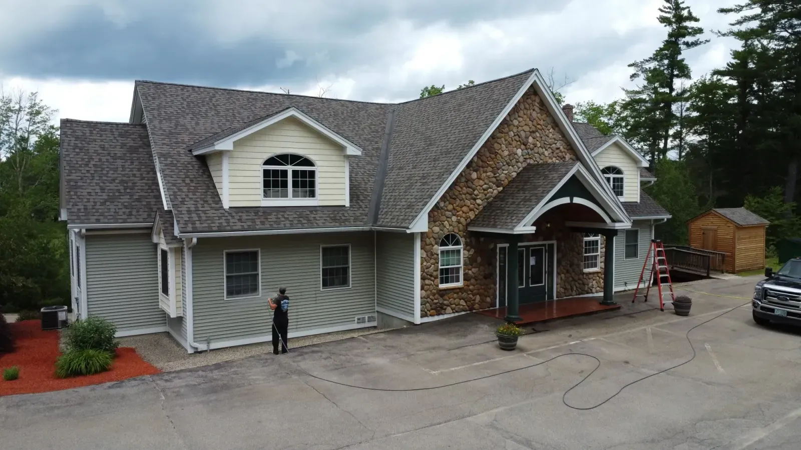 Aerial view of Black Diamond soft washing a large stone-front home in NH