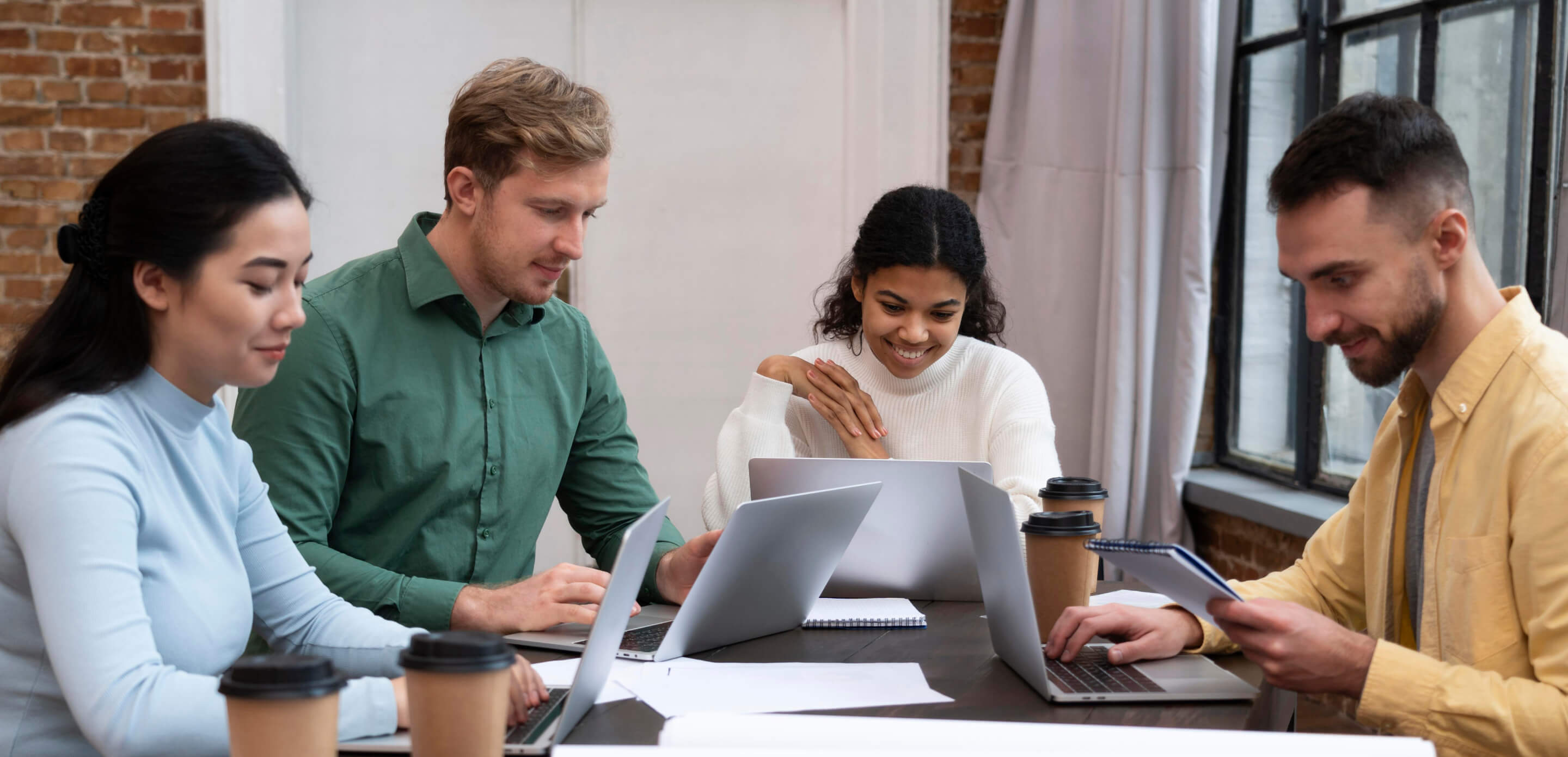 a group of people sitting around a table looking at a laptop