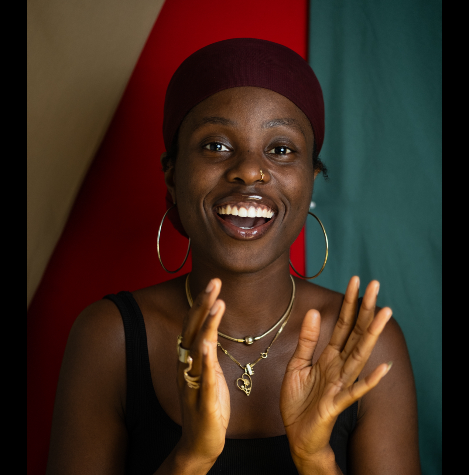 tanika smiles while looking in the camera, about to bring her hands together