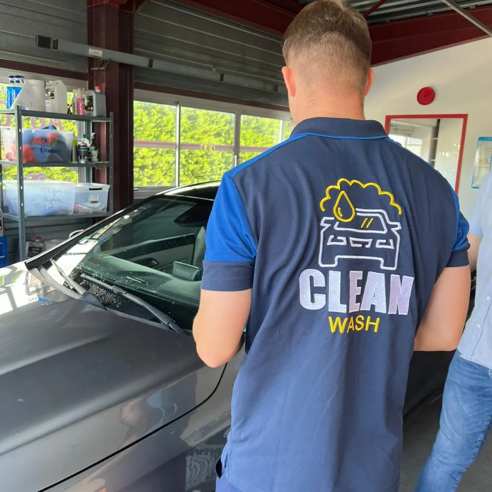 An employee wearing a polo shirt with the CleanWashAuto logo on it