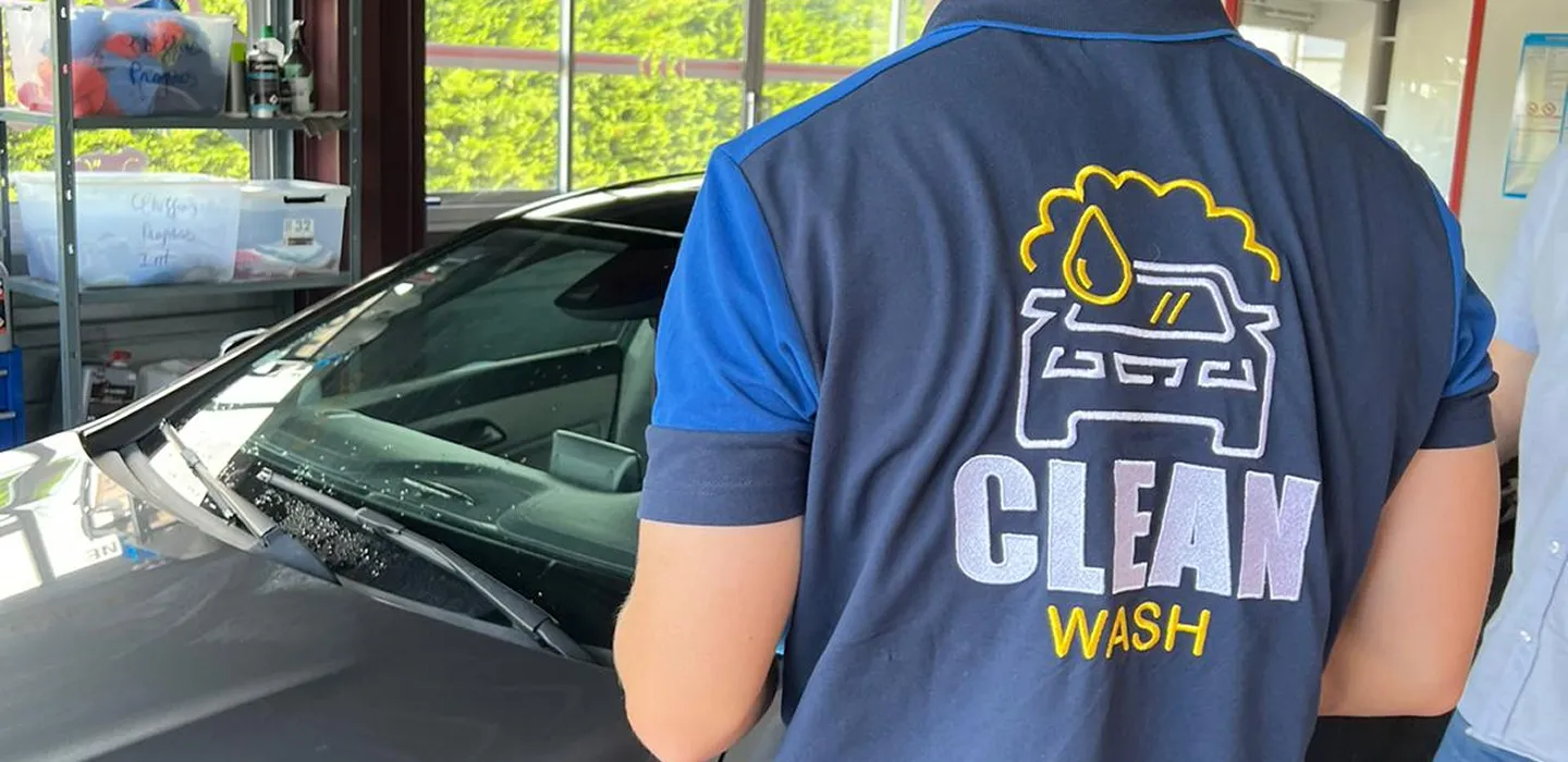 An employee wearing a polo shirt with the CleanWashAuto logo on it