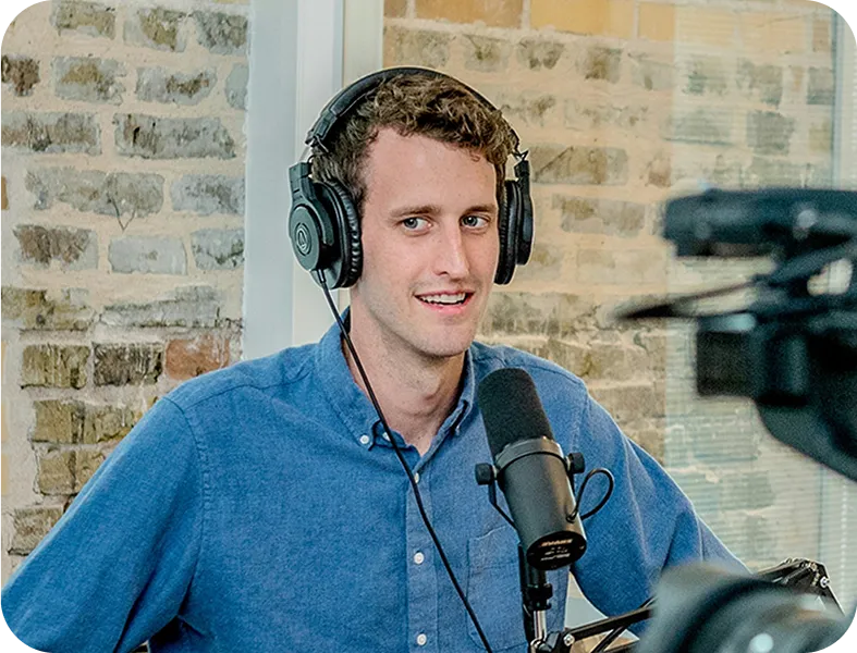 A man wearing headphones sitting in front of a microphone.