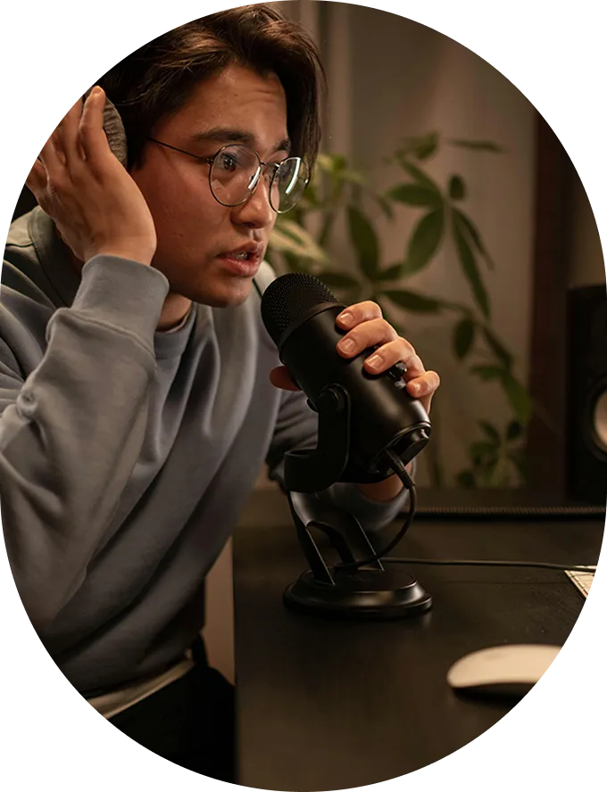 A man with glasses holding a microphone up to his ear.