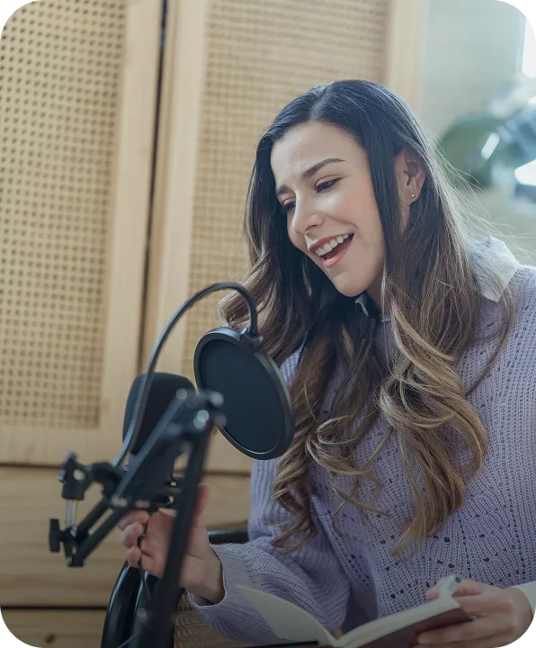 A woman sitting in front of a microphone reading a book.