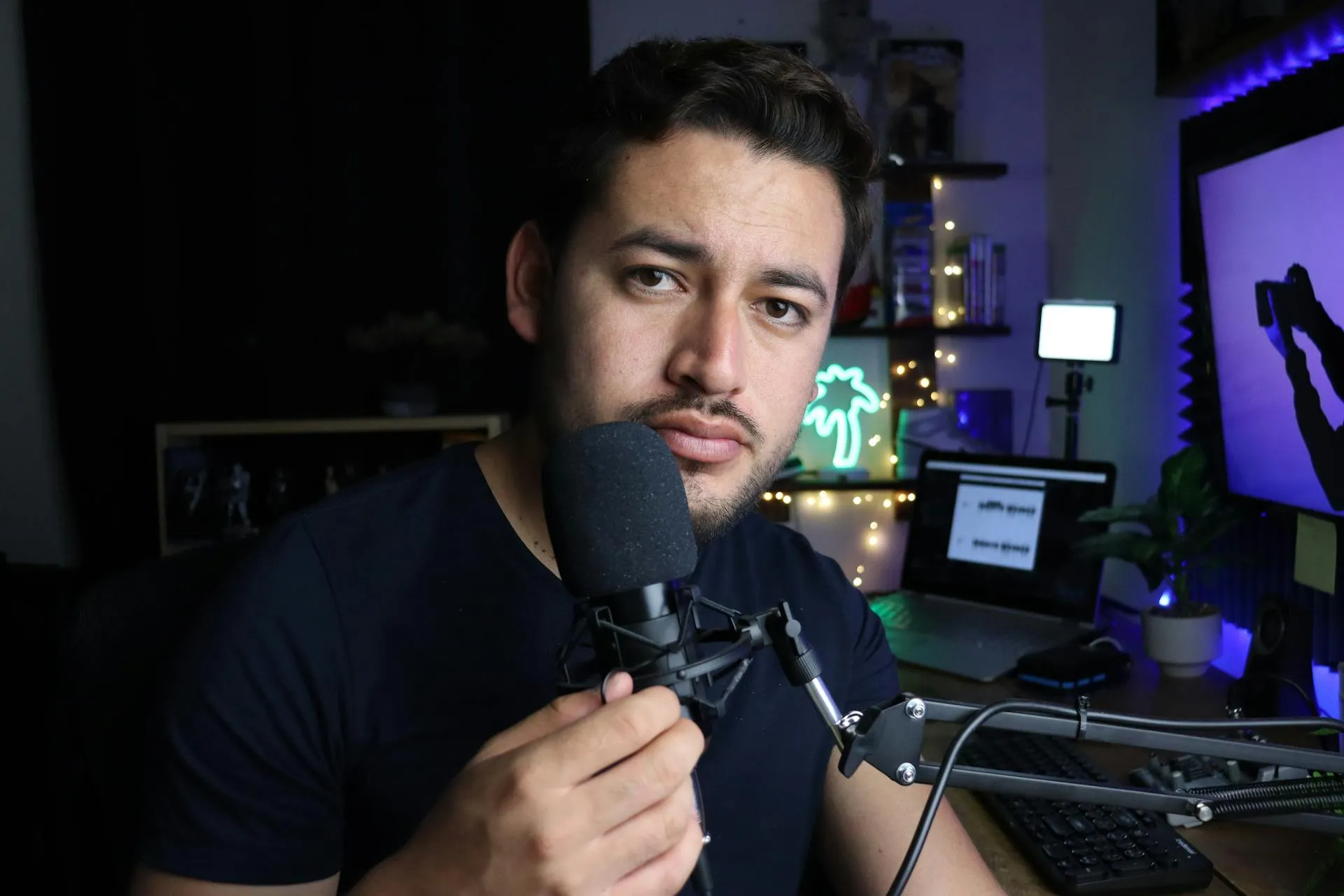A man holding a microphone in front of a computer.