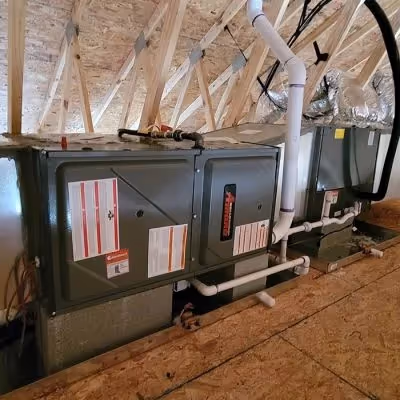 HVAC system installed in an attic, with multiple connected units, pipes, and ducts."