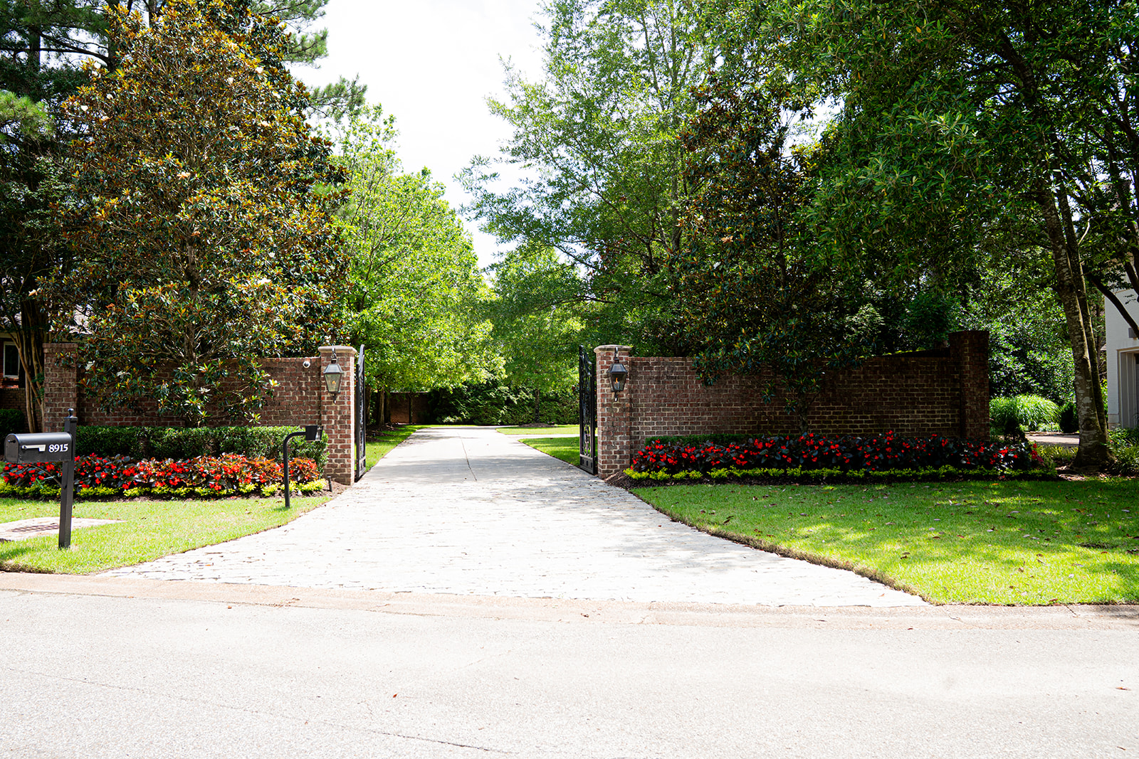 Gated driveway with brick pillars and flower beds
