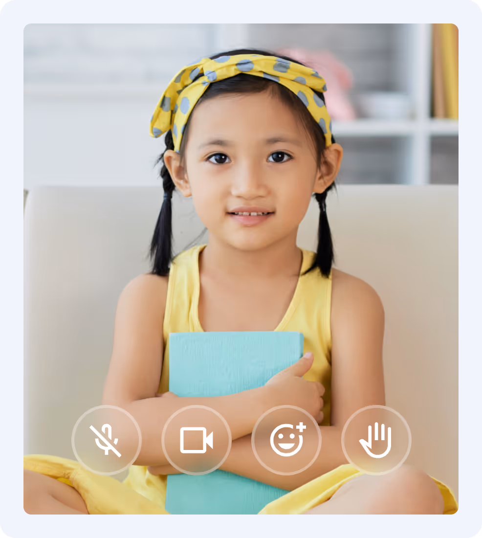 Young girl with braided hair and yellow headband sitting on a couch, holding a blue book and smiling slightly.