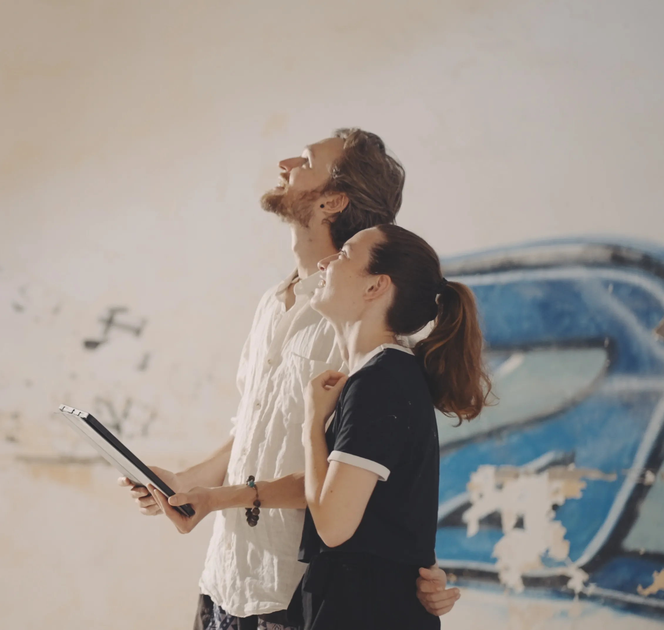 Photo d'un homme et d'une femme de profil, regardant vers le haut, l'homme tient une tablette dans ses mains.