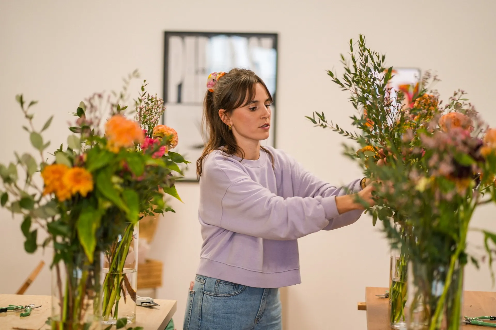 Photo d'une femme dans une pièce, un bouquet de fleurs de chaque côté d'elle.