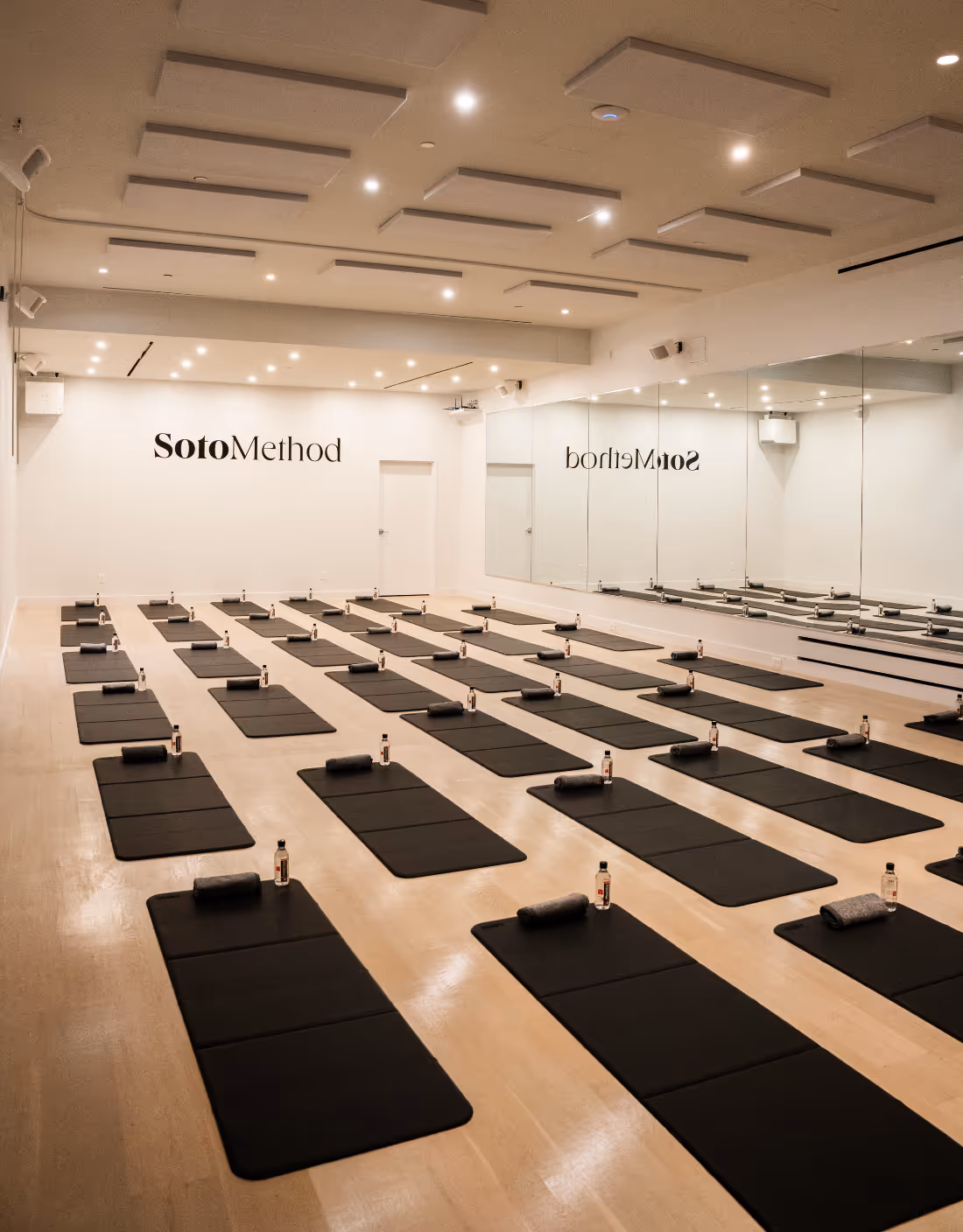 Image of inside the Sotomethod studio filled with black yoga mats laid out