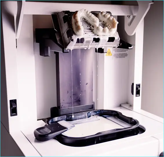 Female scientist in white lab coat operating lab equipment in a bright laboratory.