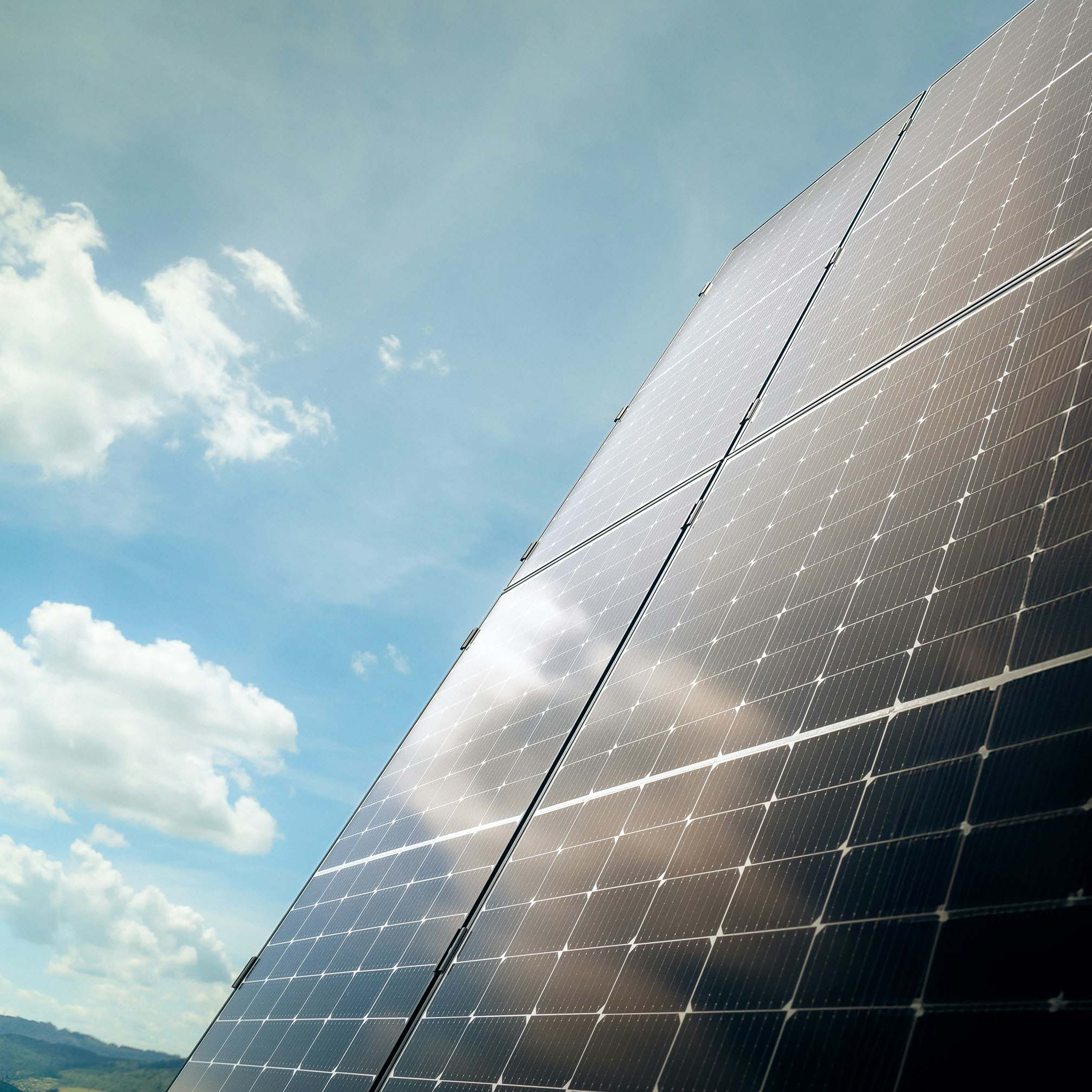 Nahaufnahme von Solarpanels unter einem blauen Himmel mit weißen Wolken.
