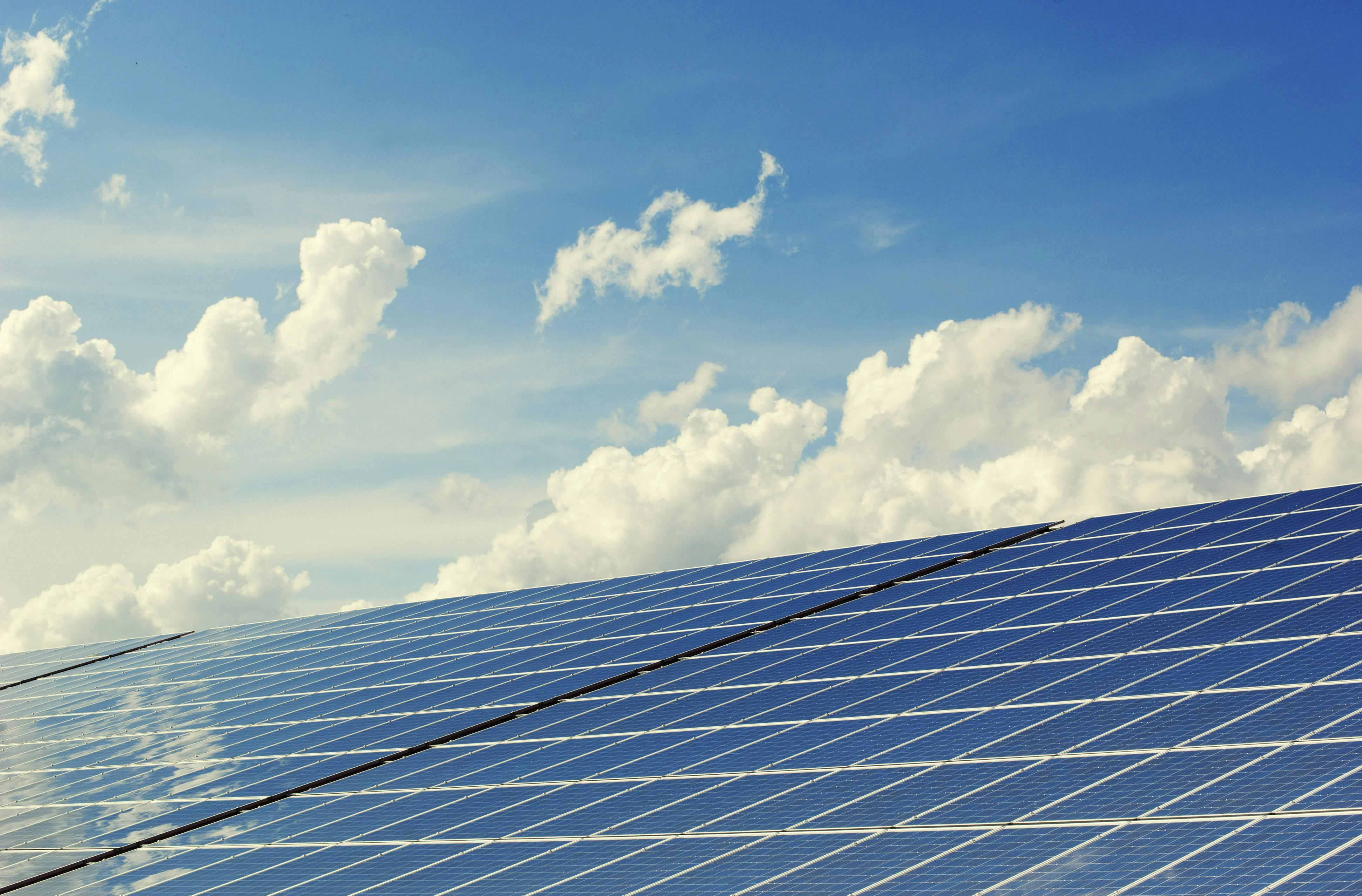 Weitläufige blaue Solarpanel-Felder unter einem bewölkten Himmel.