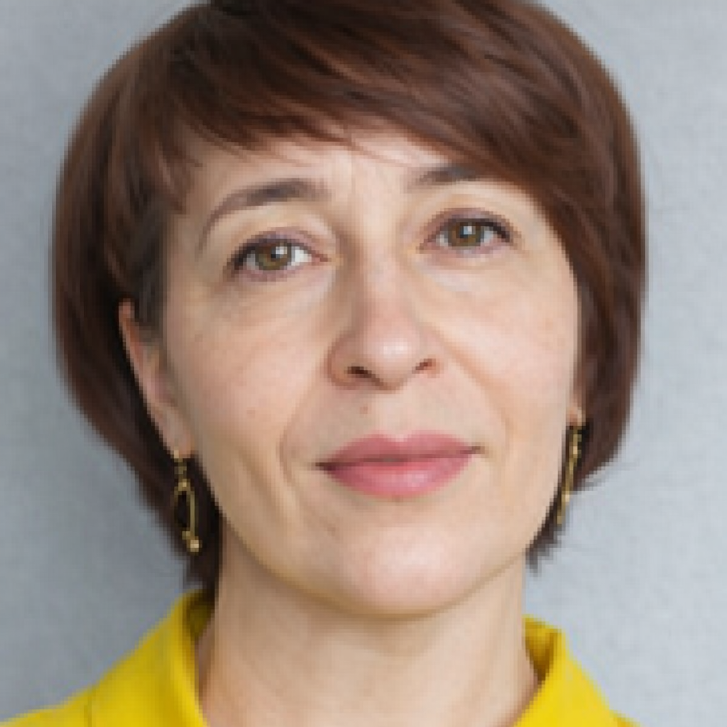 Portrét ženy se světle hnědými vlasy, zlatými náušnicemi a žlutým oděvem.