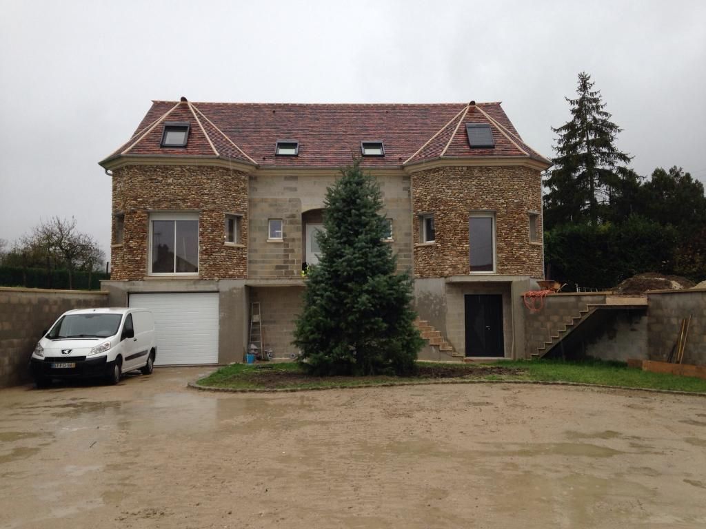 Maison en construction avec toit en tuiles rouges, murs en pierre 