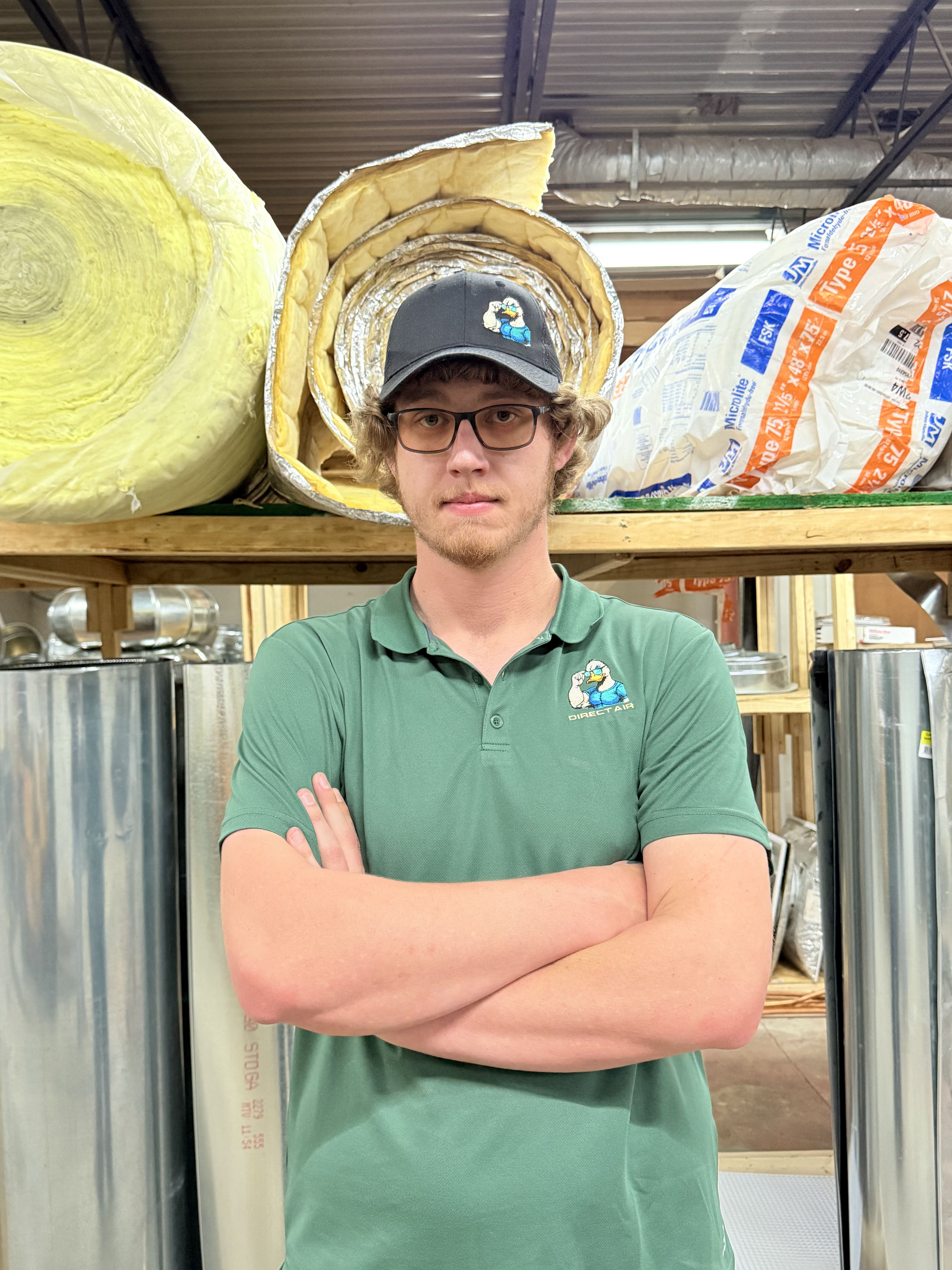 Worker standing in warehouse with insulation rolls and metal supplies