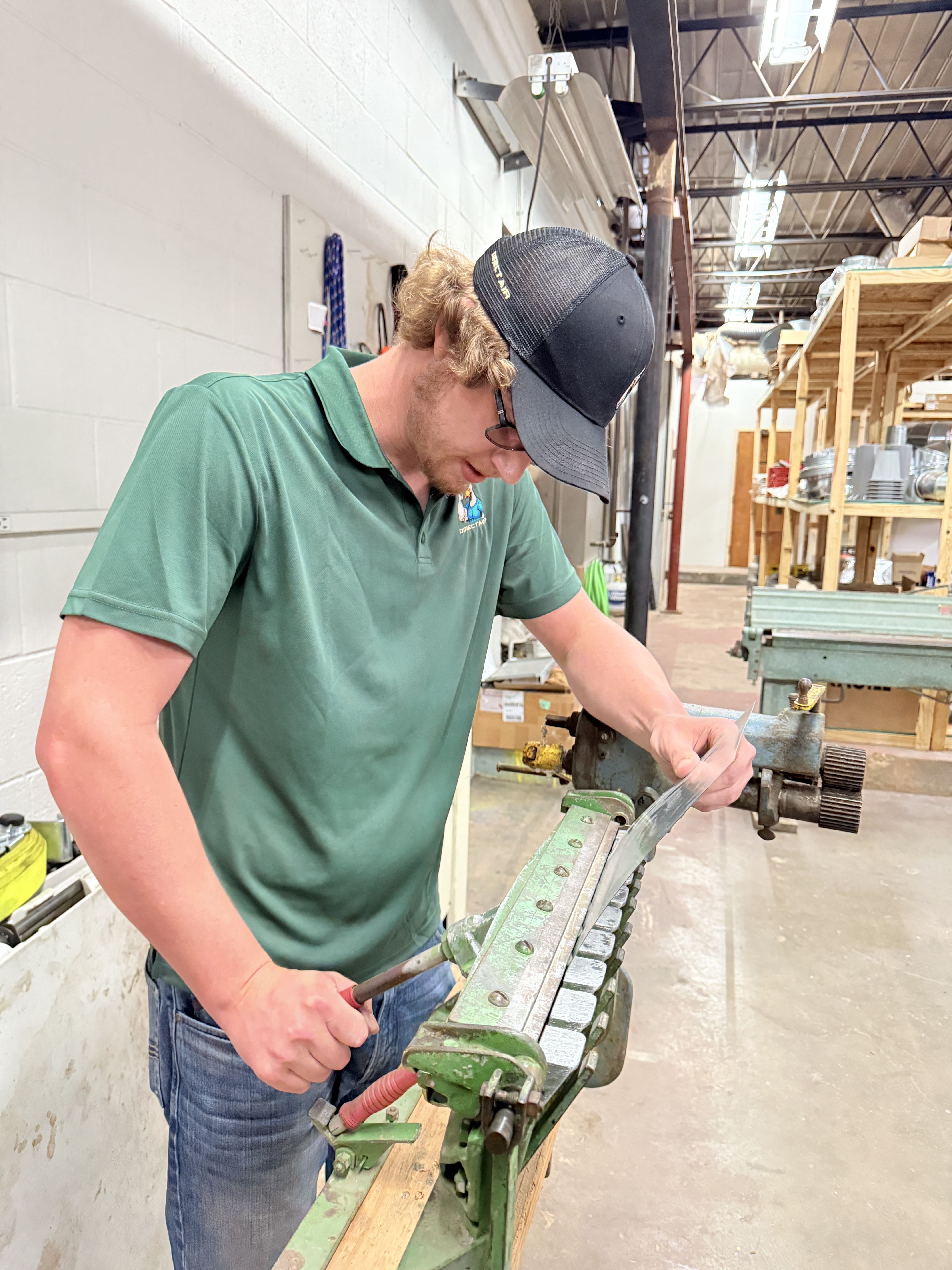 Worker operating green metal machinery in industrial workshop