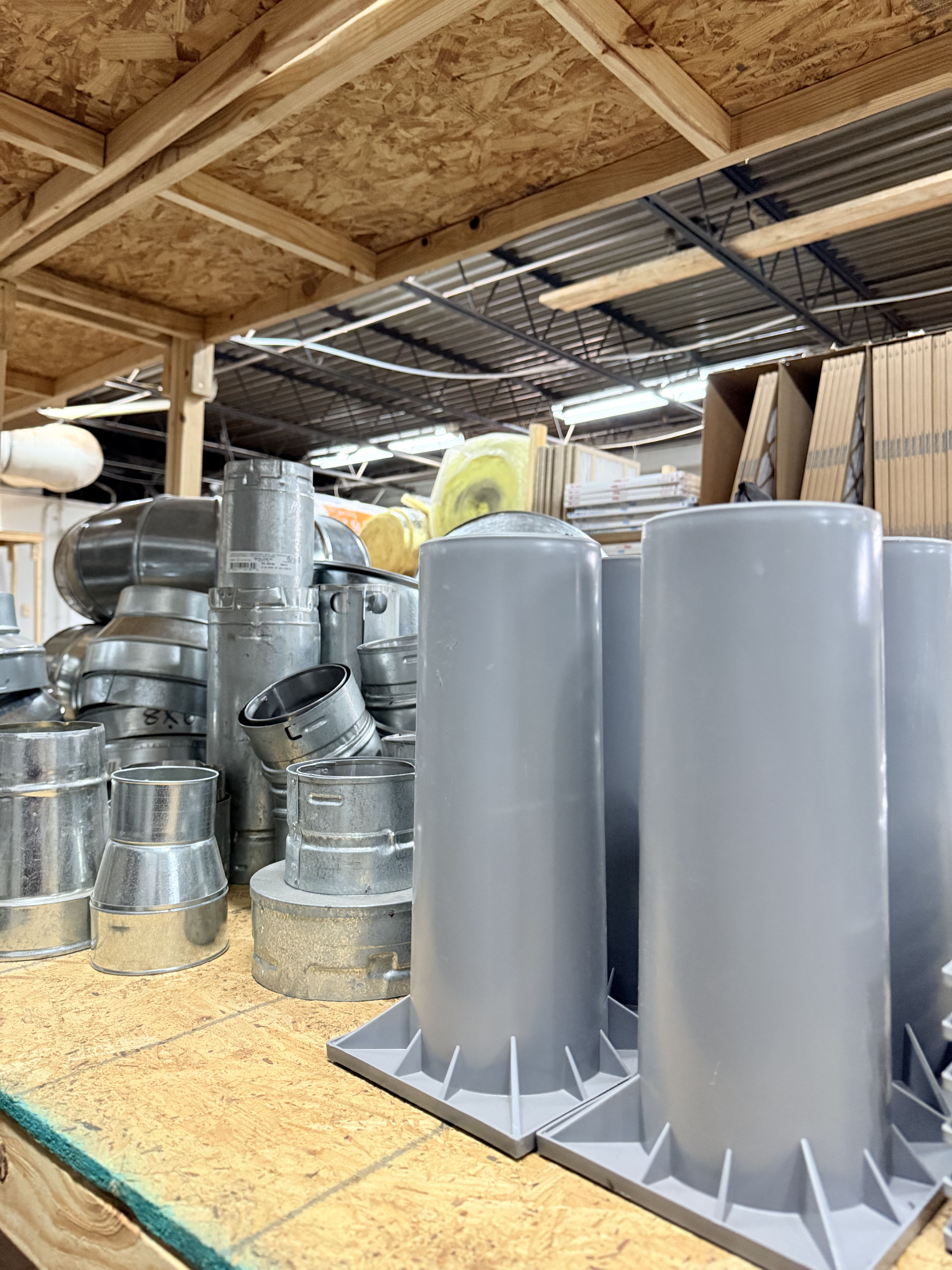 Metal ventilation ducts and pipes stacked in industrial warehouse storage