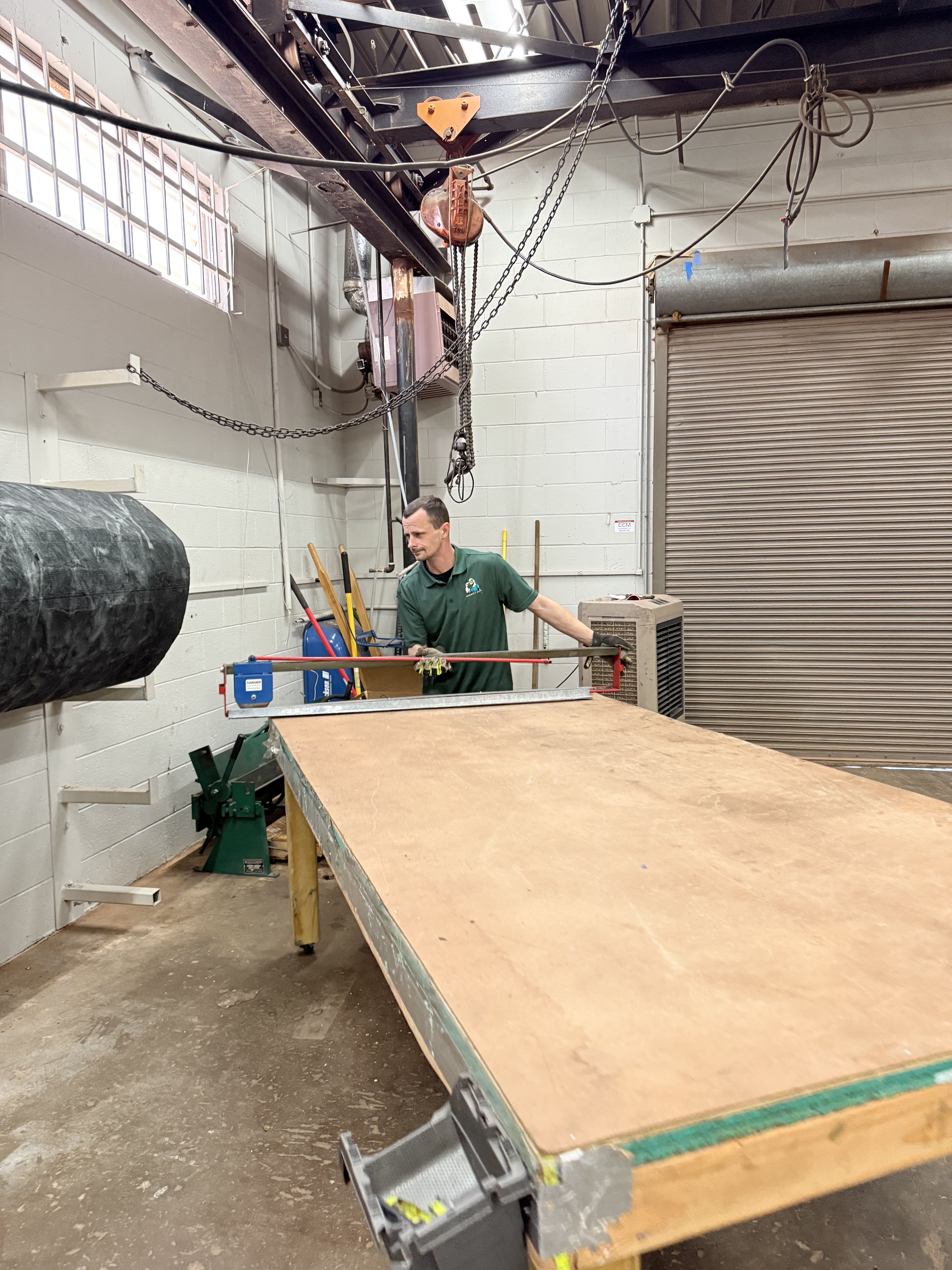 Worker in workshop with overhead crane and large wooden workbench