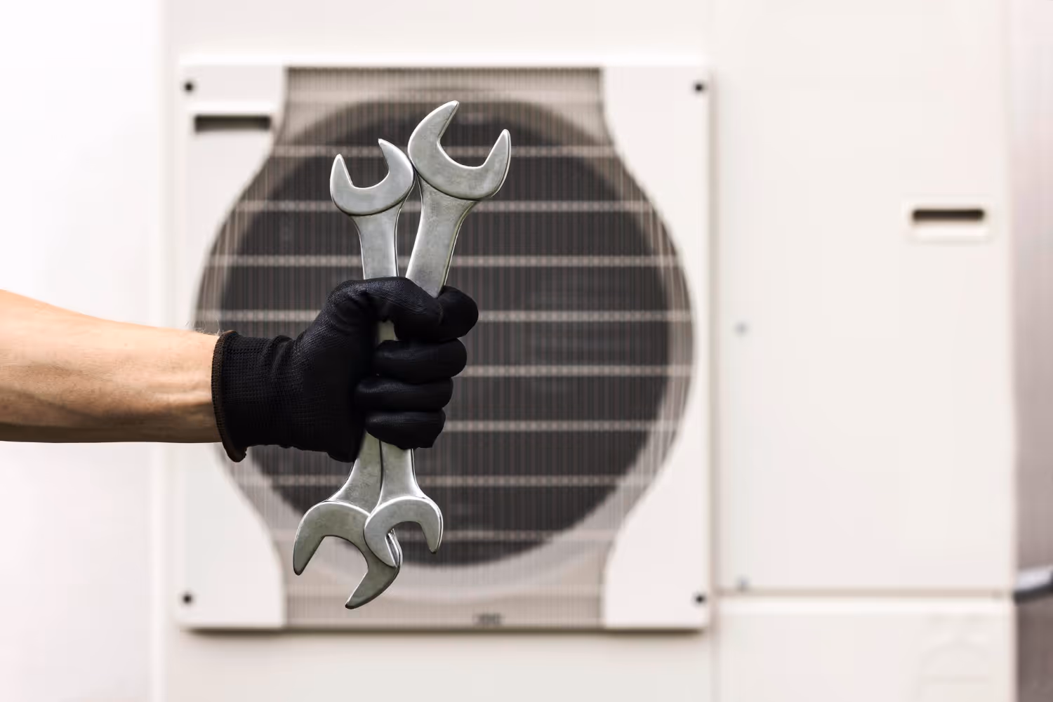 Hand in black glove holding wrenches in front of solar panel