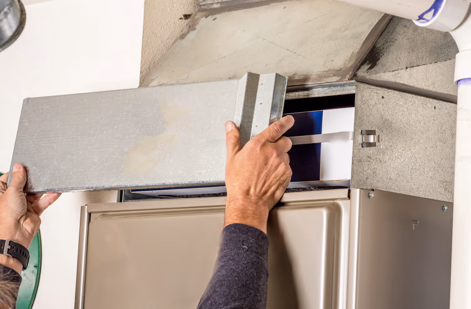 Hands installing or adjusting a metal vent cover on an HVAC system