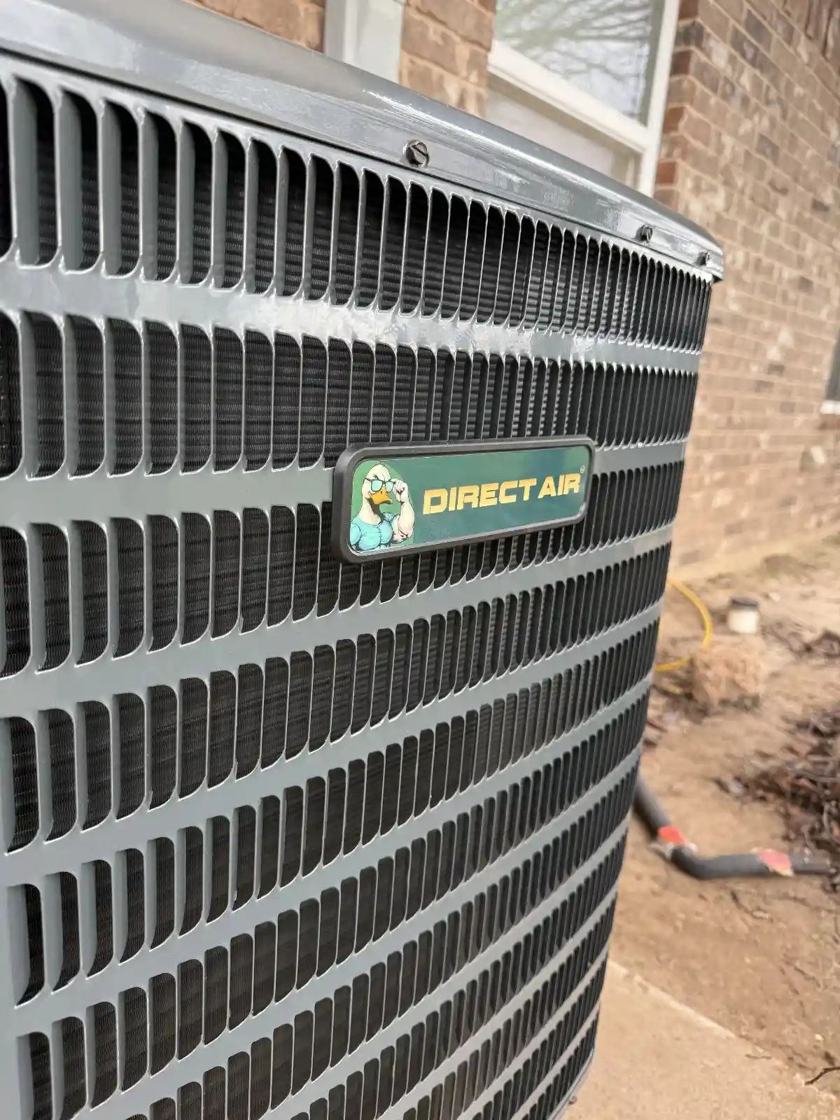 Direct Air HVAC unit with mascot logo on side, placed near brick wall