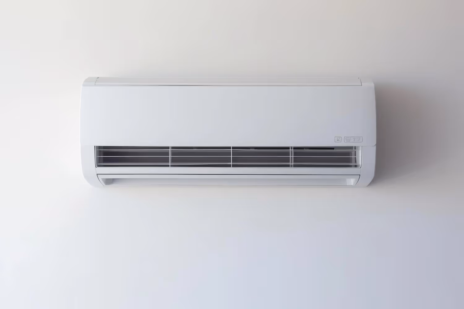White wall-mounted air conditioning unit with ventilation grille