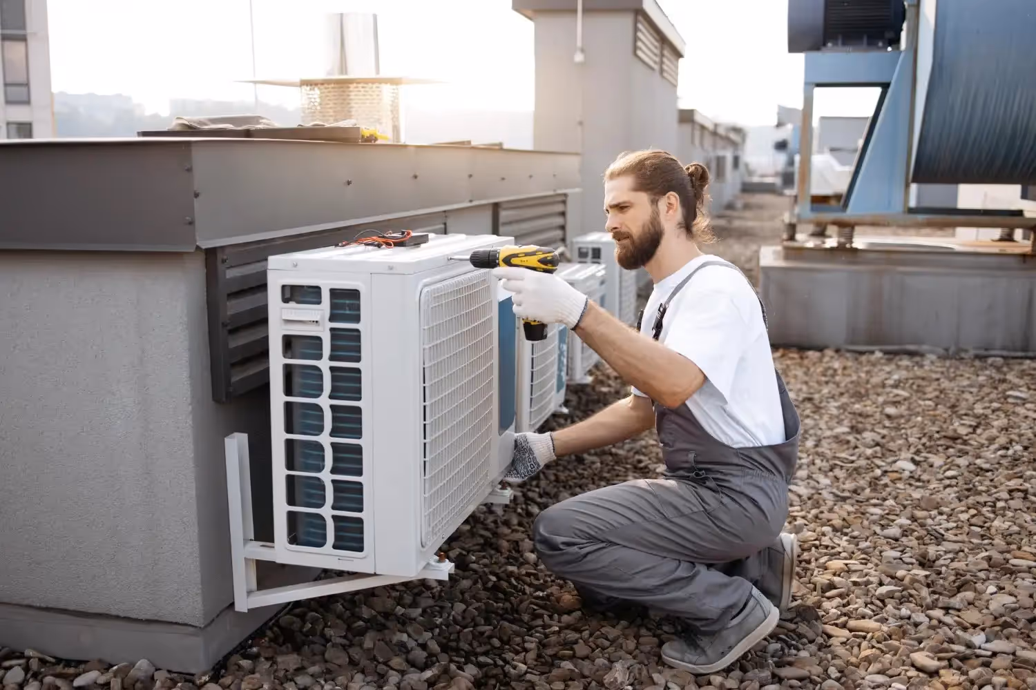 Technician repairing air conditioning unit on rooftop with tools