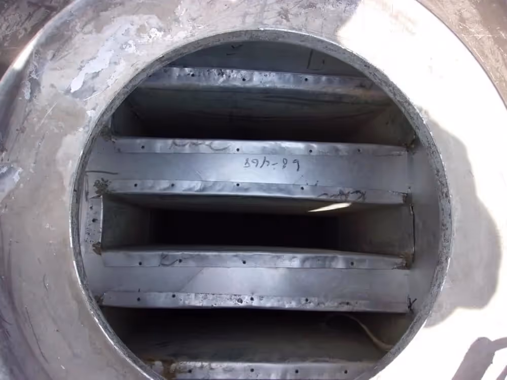 Industrial metal pipe interior with horizontal dividers and perforated surfaces