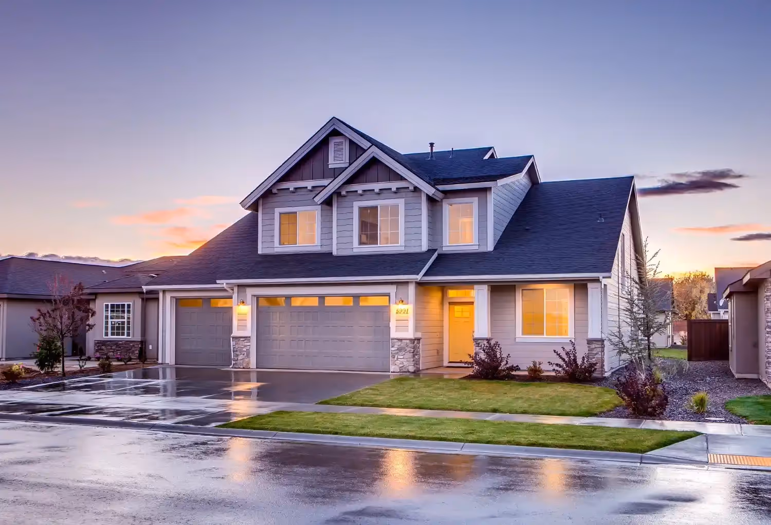 Modern suburban two-story house with glowing windows at sunset