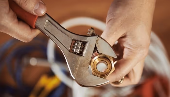 Adjustable wrench tightening a nut with hands gripping tool