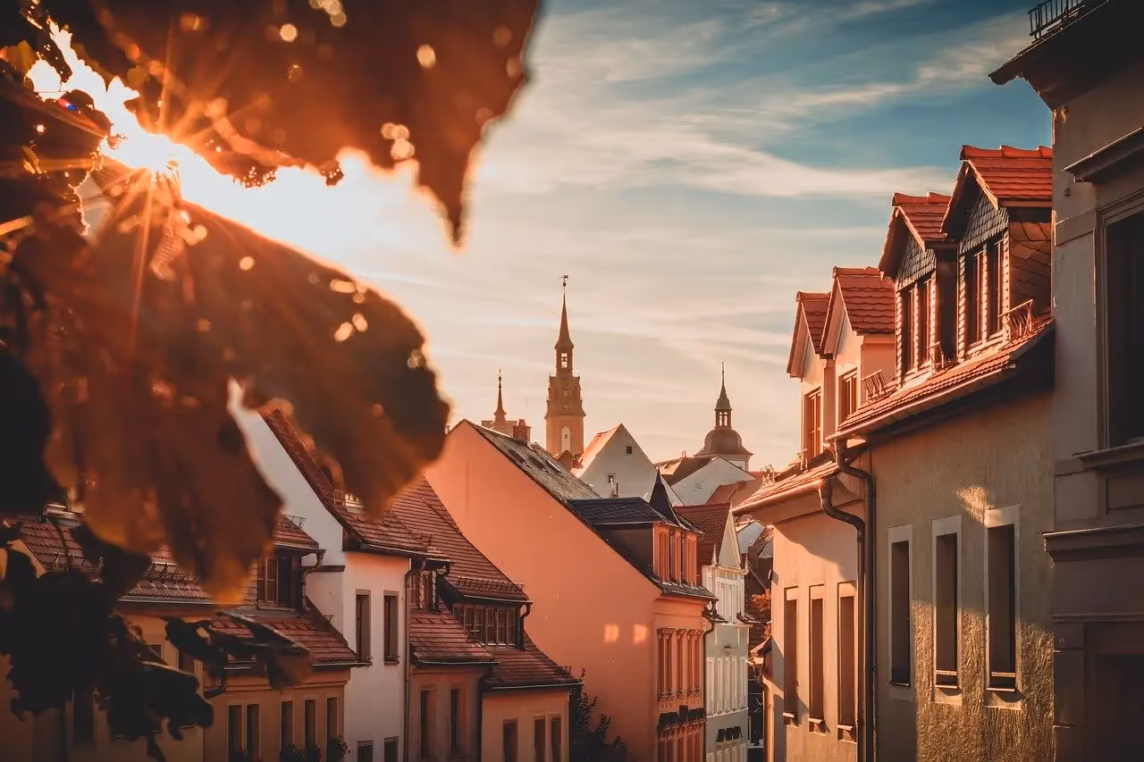 Sunlit European town with church towers and red-tiled roofs at golden hour