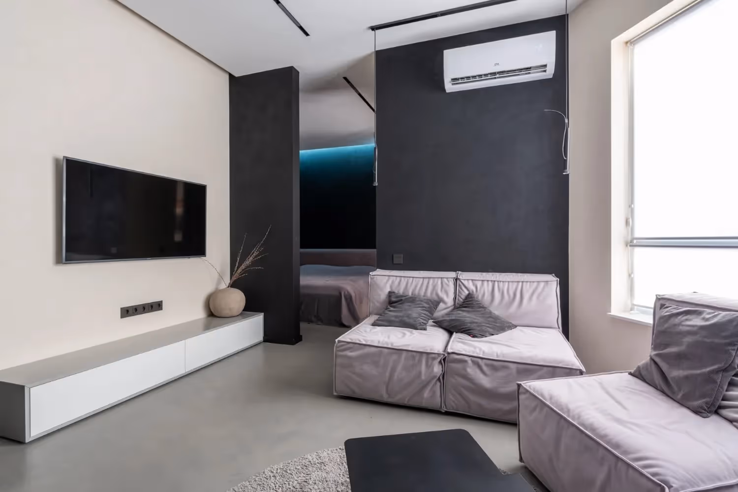 Modern minimalist studio apartment with gray sofa and black accent walls