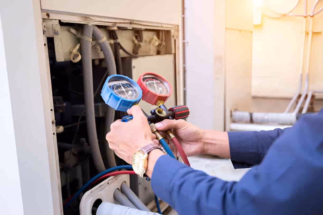 Technician checking pressure gauges on air conditioning system