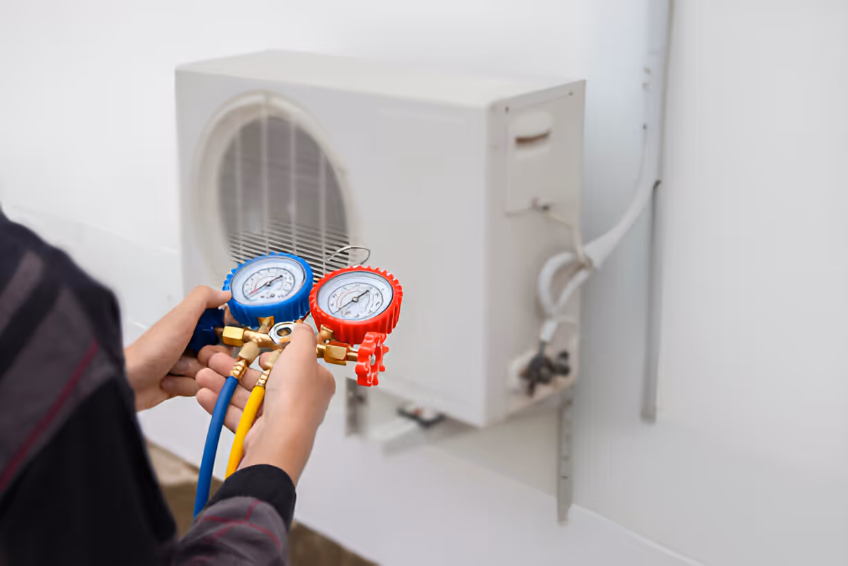 Technician checking air conditioning unit with pressure gauges