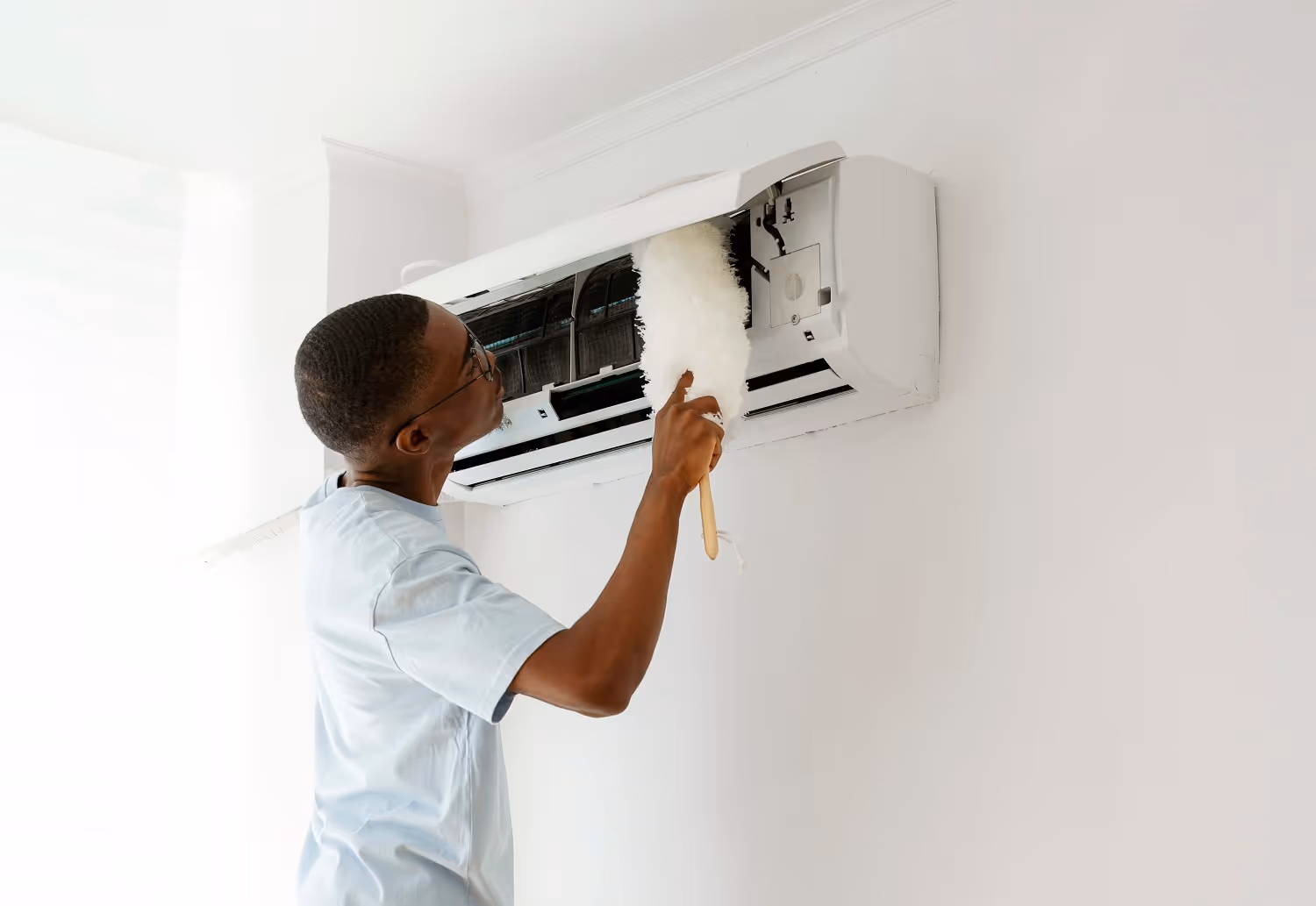 Technician cleaning and maintaining wall-mounted air conditioning unit