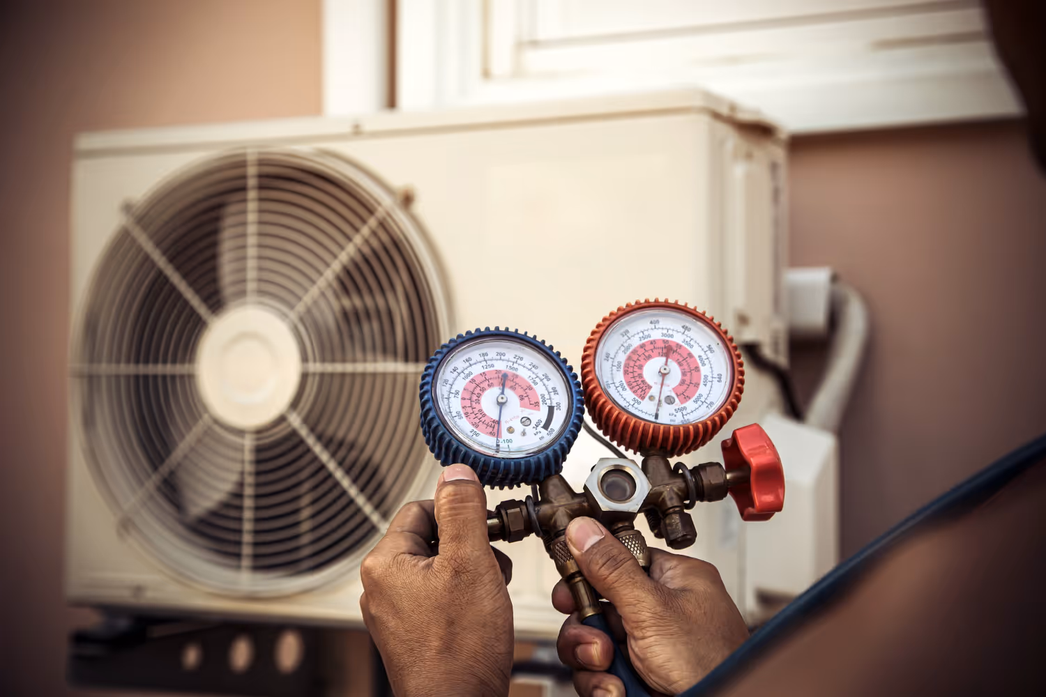 Technician checking air conditioning unit pressure with gauge manifold