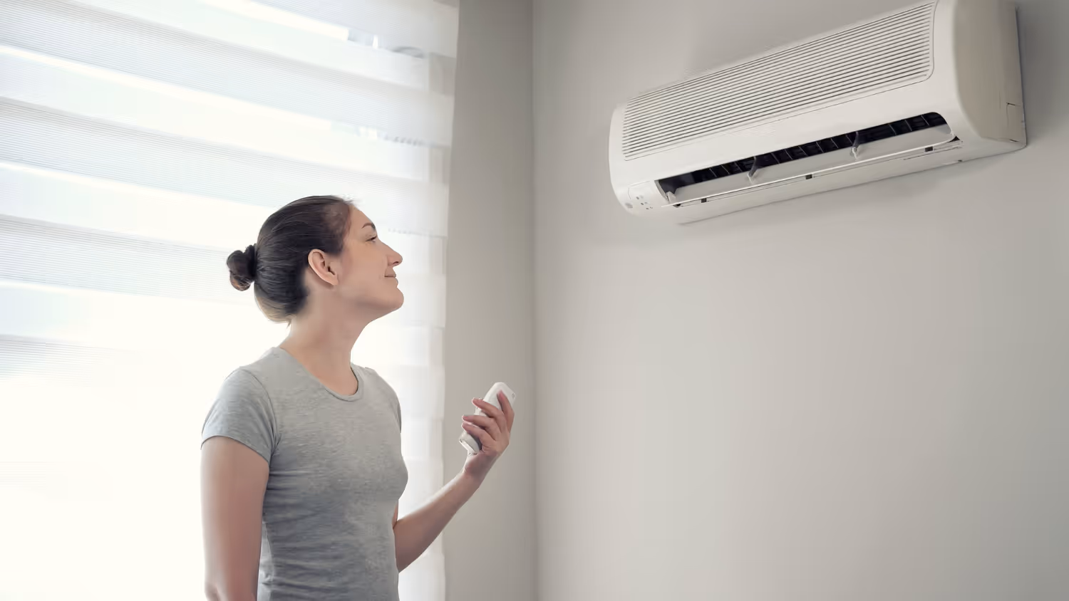 Person enjoying cool air from wall-mounted air conditioning unit