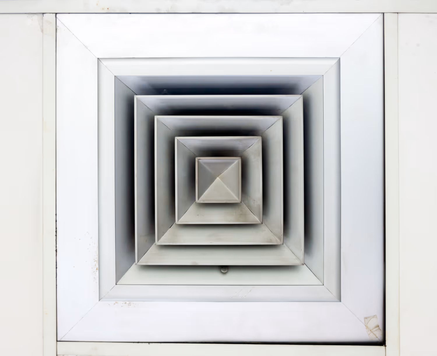 White square air vent with concentric geometric layers and pyramid center