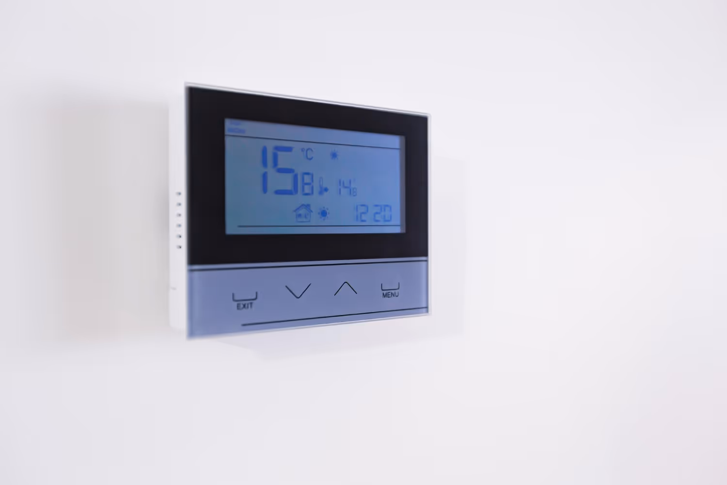 Digital thermostat displaying temperature, humidity, and time on white wall
