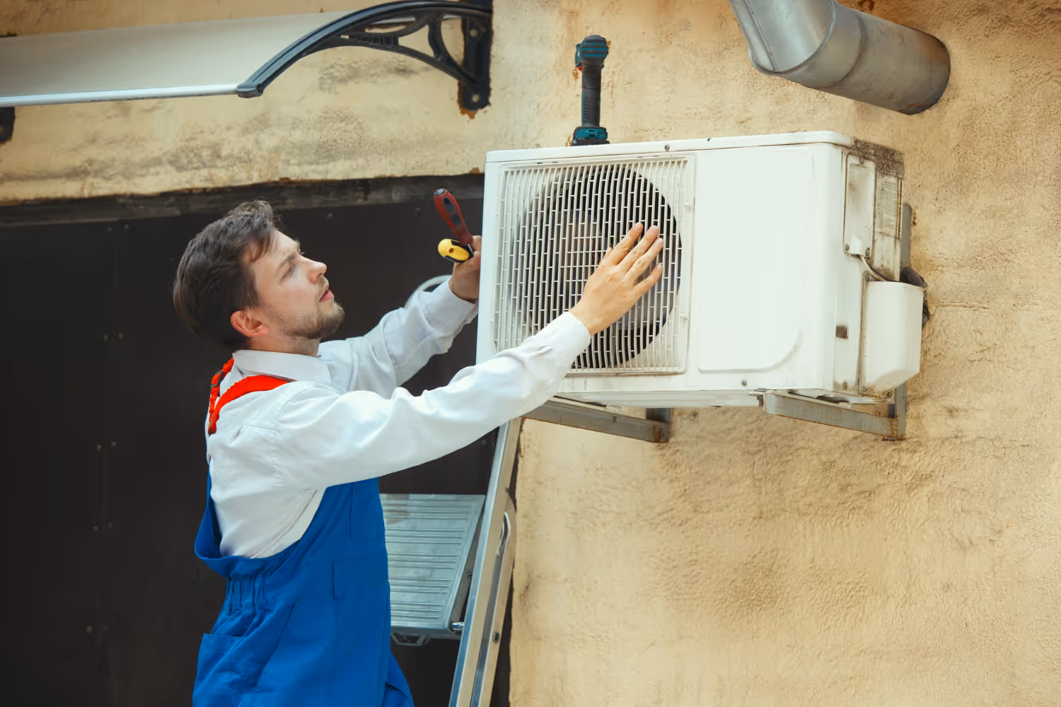 Technician repairing air conditioning unit on exterior wall