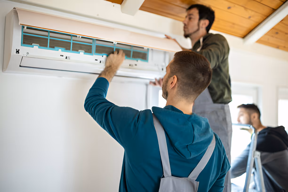 Technicians installing air conditioning unit on wooden-ceiling wall