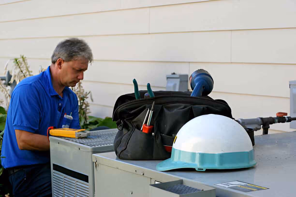 Technician working with tools and safety helmet near industrial equipment
