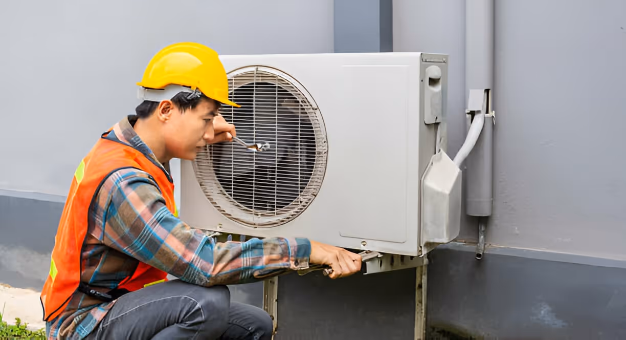 Technician in safety gear repairing an outdoor air conditioning unit